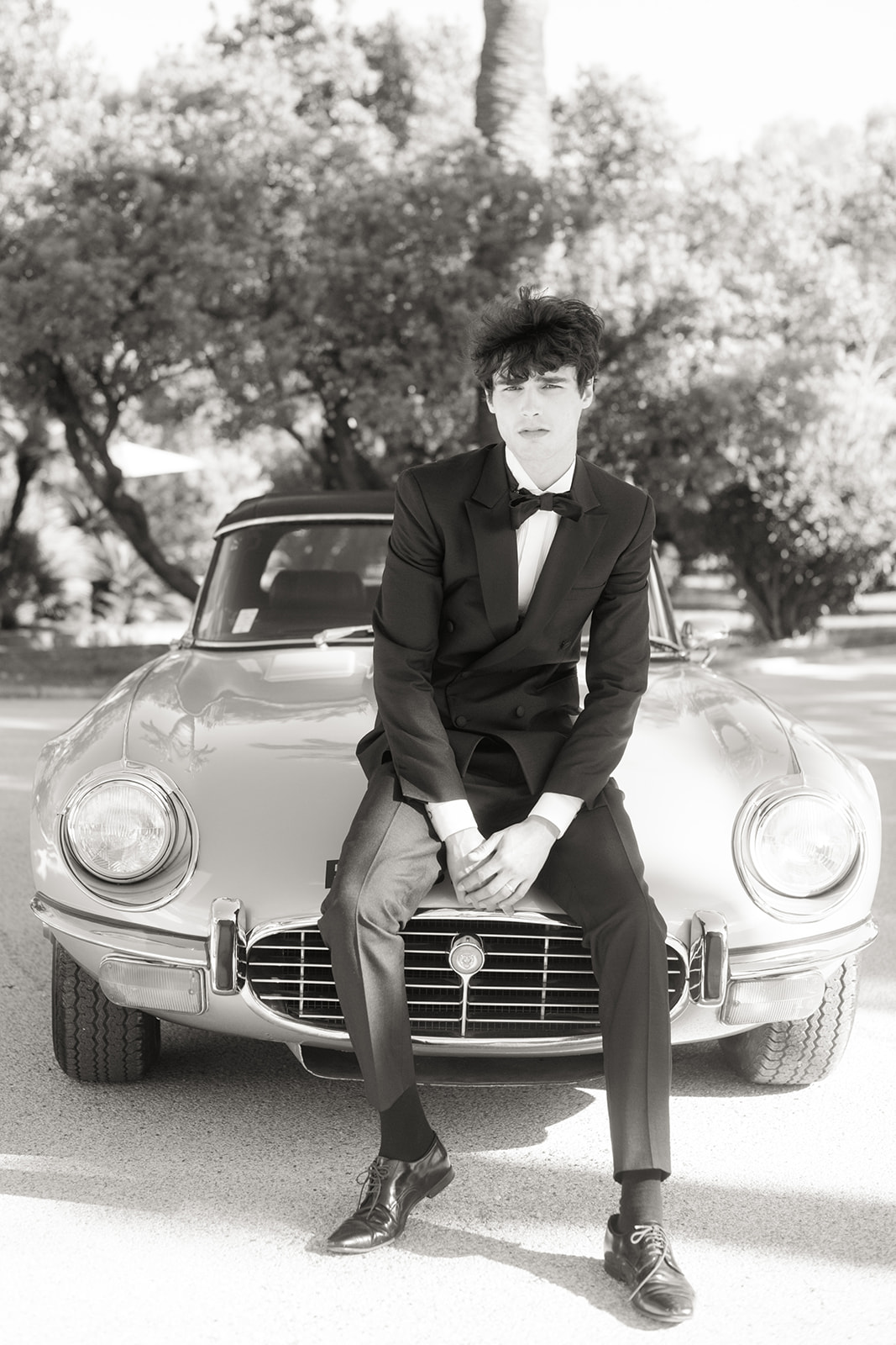 Black-and-white groom portrait seated on a classic Jaguar near Saint-Tropez